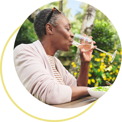 African American woman drinking wine with her meal outside